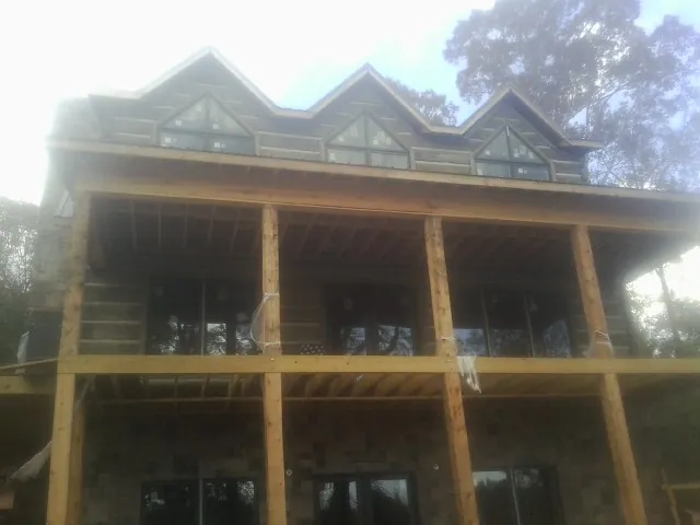 Dormers and porch framing on a large log home under construction — Roof Coating work by our crew in Glyndon