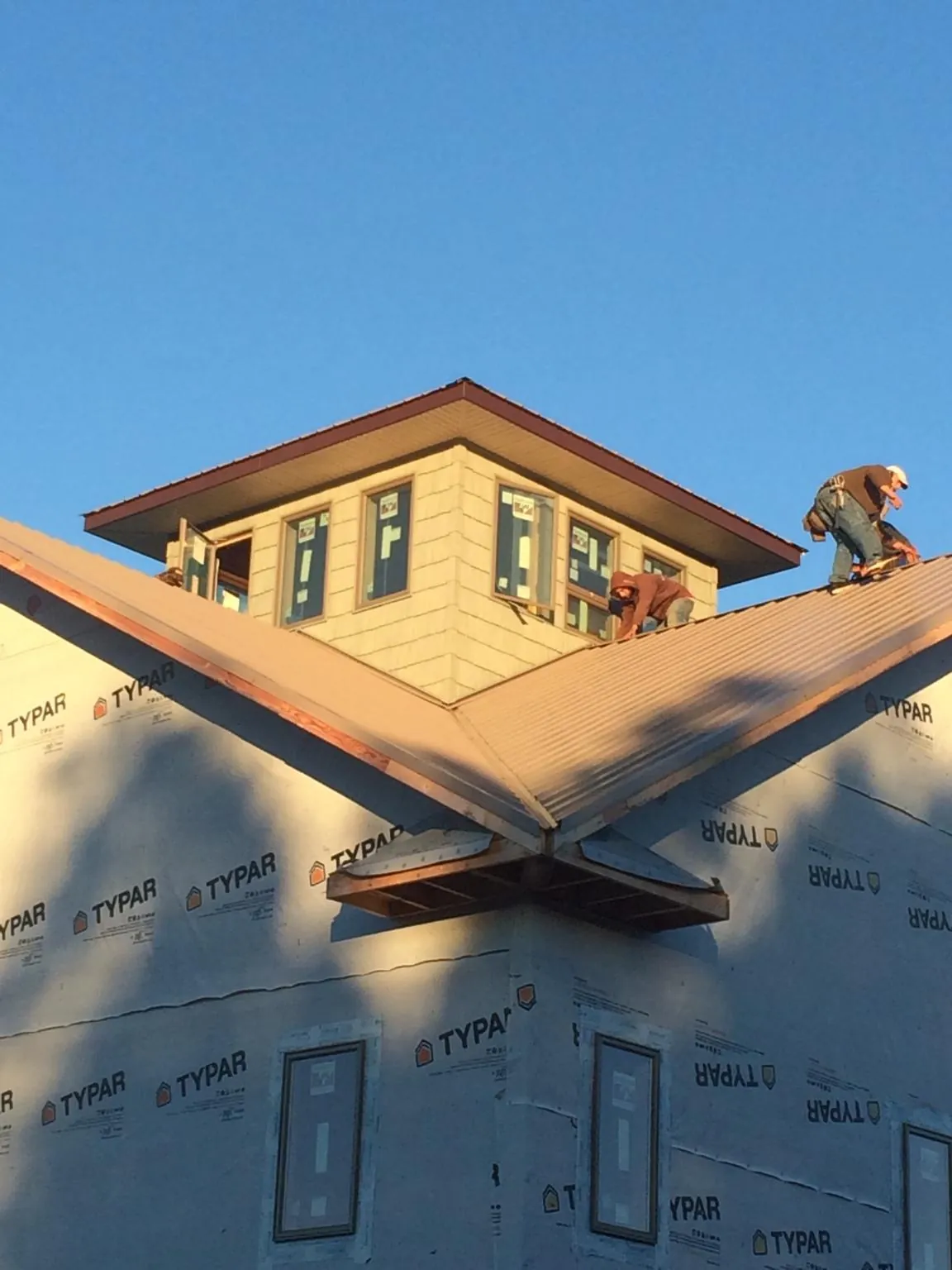 Roofers working around a rooftop cupola on a new metal roof at sunset — Roof Waterproofing in Glyndon by Roofing Brothers